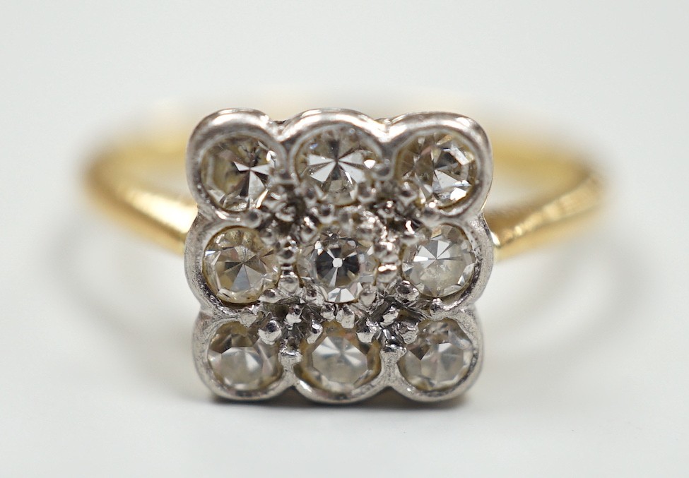 An 18ct and collet set nine stone diamond cluster table ring, size K/L, gross weight 2.6 grams.